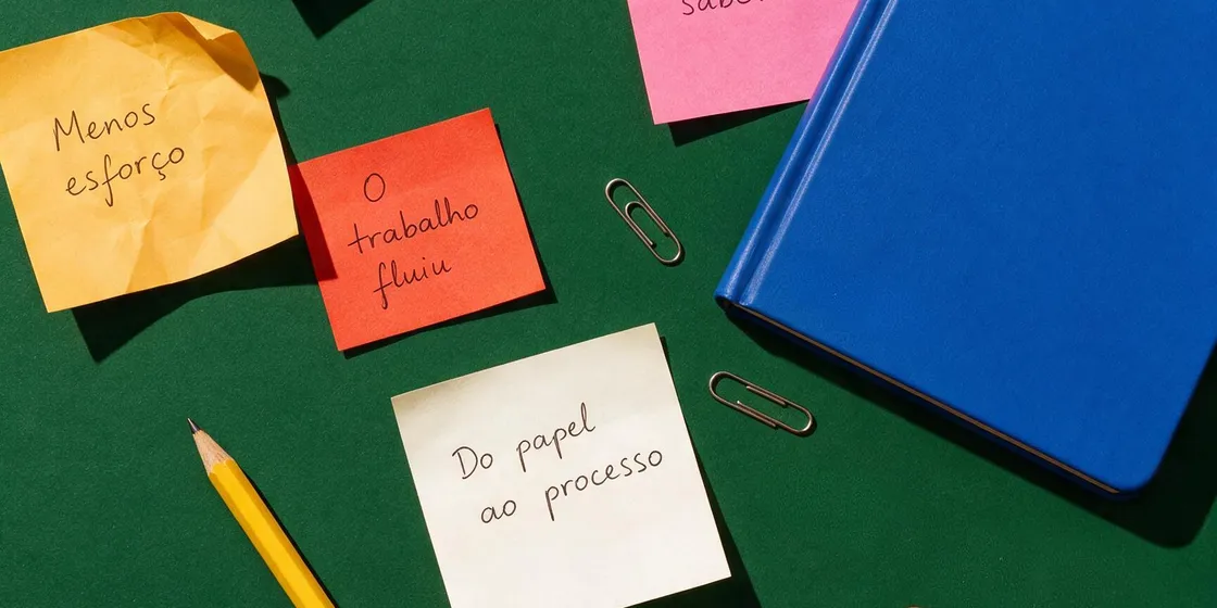 Post-its coloridos com anotações de processo sobre uma mesa de trabalho verde.
